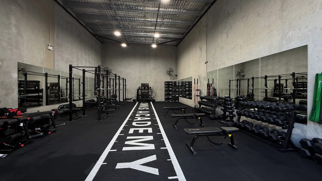 Interior of a gym with weightlifting equipment and mirrored walls.