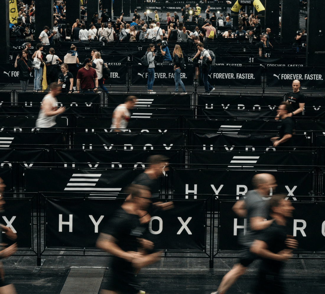 Crowd of runners participating in a HYROX fitness event indoors.