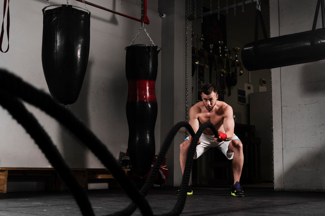 Person exercising with battle ropes in a gym setting.