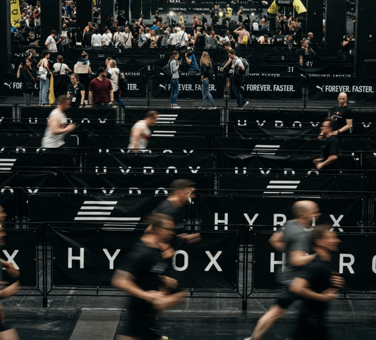 Crowd of runners participating in a HYROX fitness event indoors.